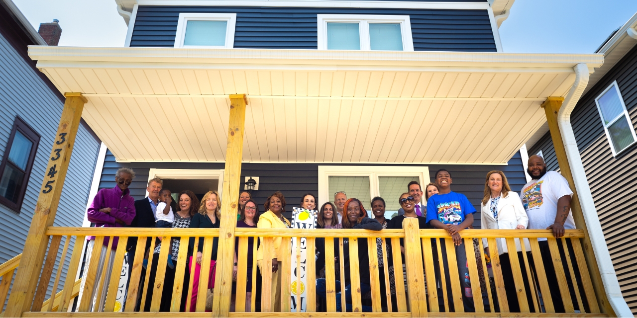 Baird Advisors team standing on the front porch of a Habitat for Humanity house with the homeowners.